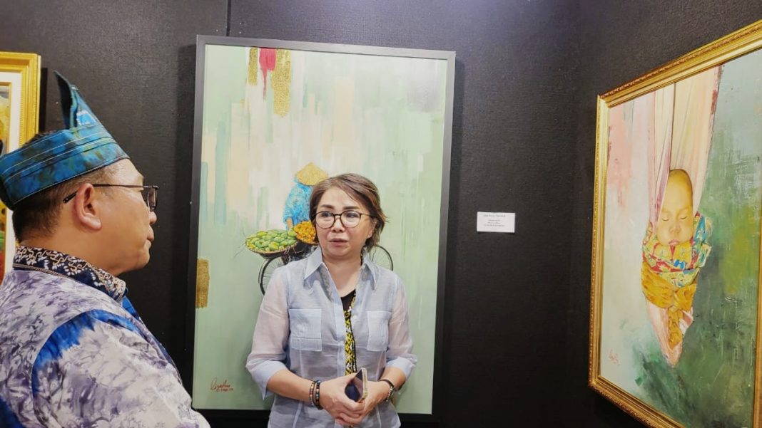 Pelukis Lisa Arne Senduk terlihat menjelaskan karya lukisannya kepada Sekretaris Dinas Pendidikan dan Kebudayaan Provinsi Kalimantan Selatan, Hadeli Rosyaidi,M.Pd saat peresmian Pameran Lukisan di Anjungan TMII (26/05).